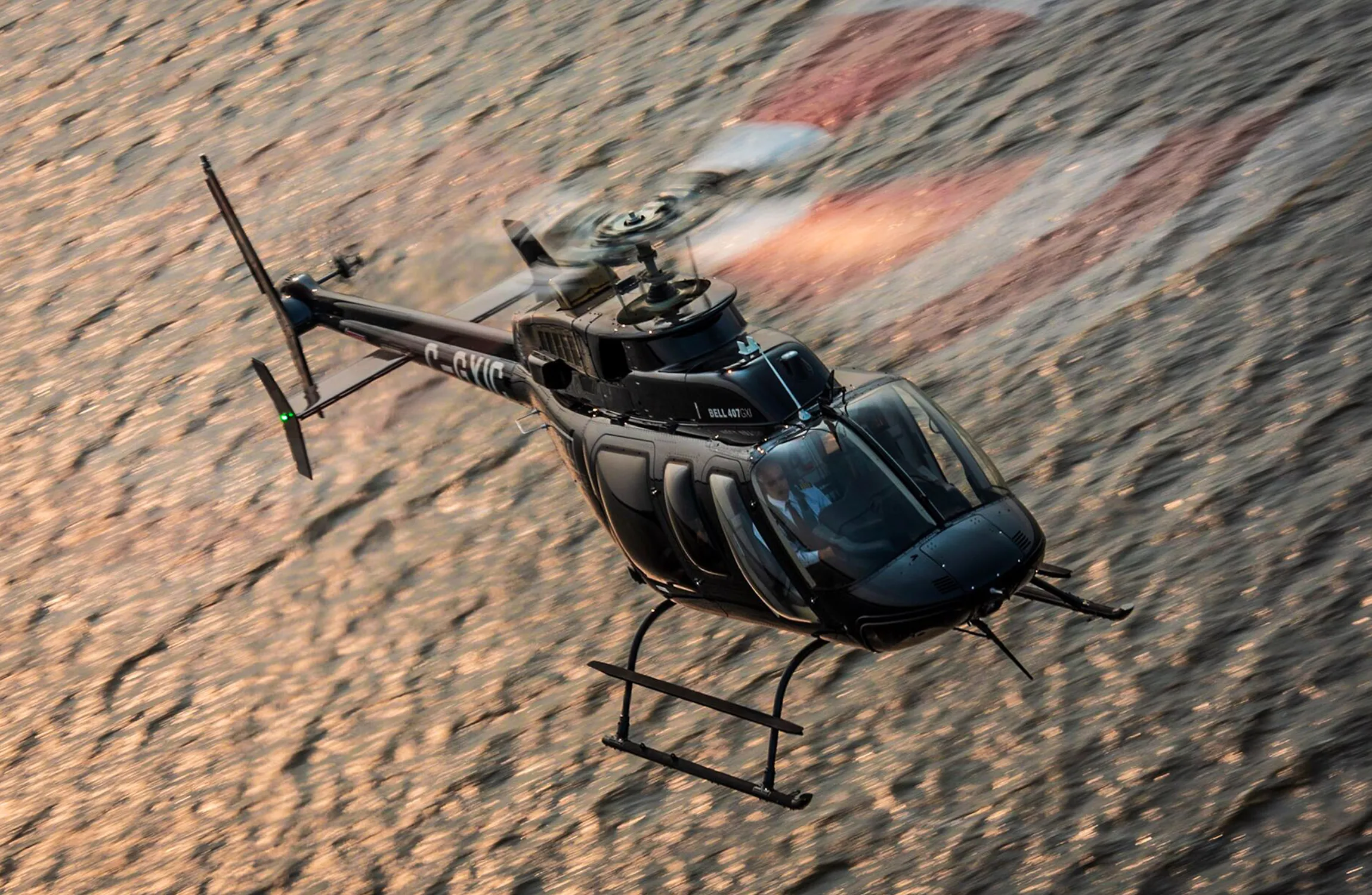A black helicopter flying over water