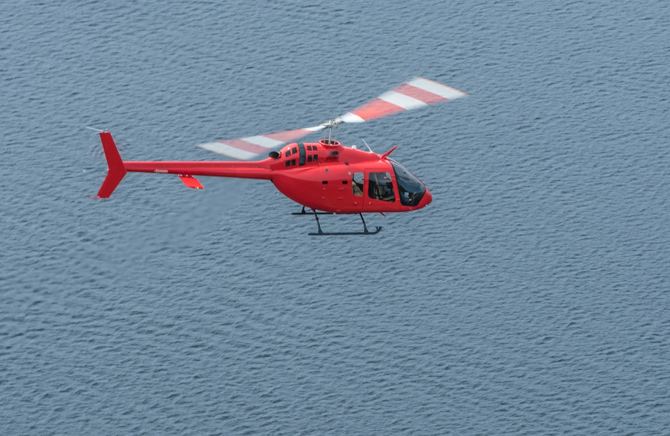 A red helicopter flying over water