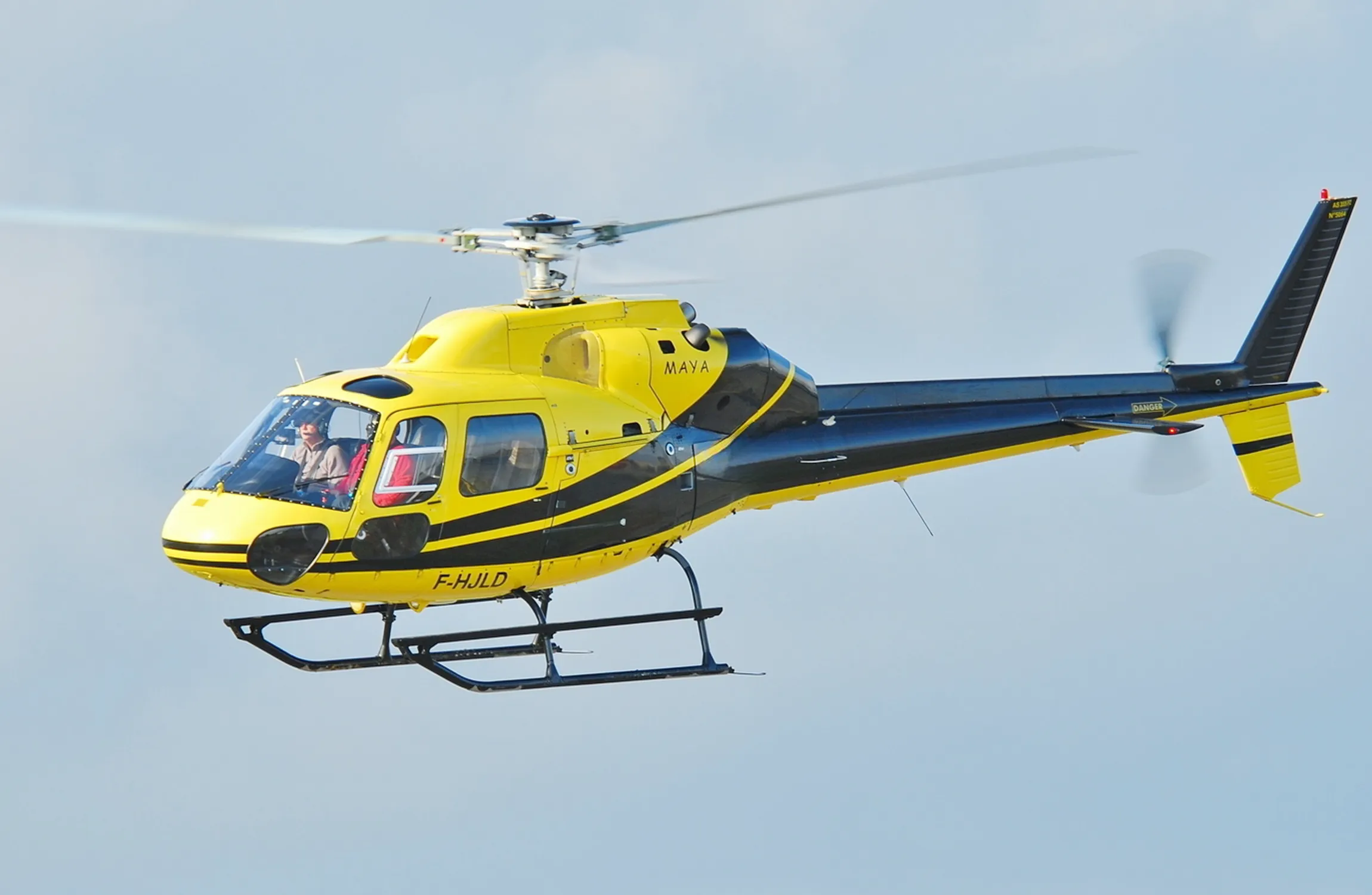 A yellow and black helicopter in the air