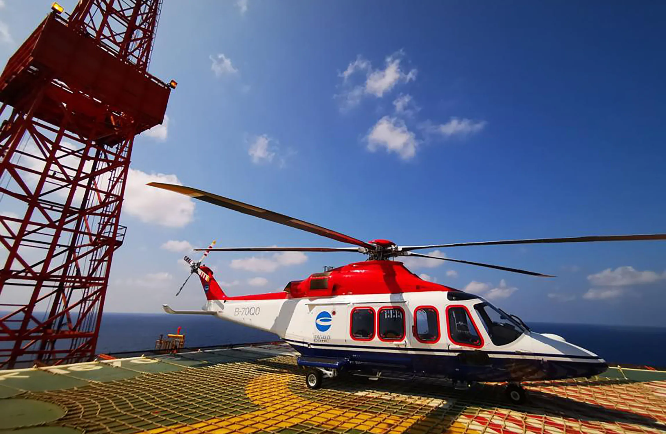 A red and white helicopter parked on an oil rig