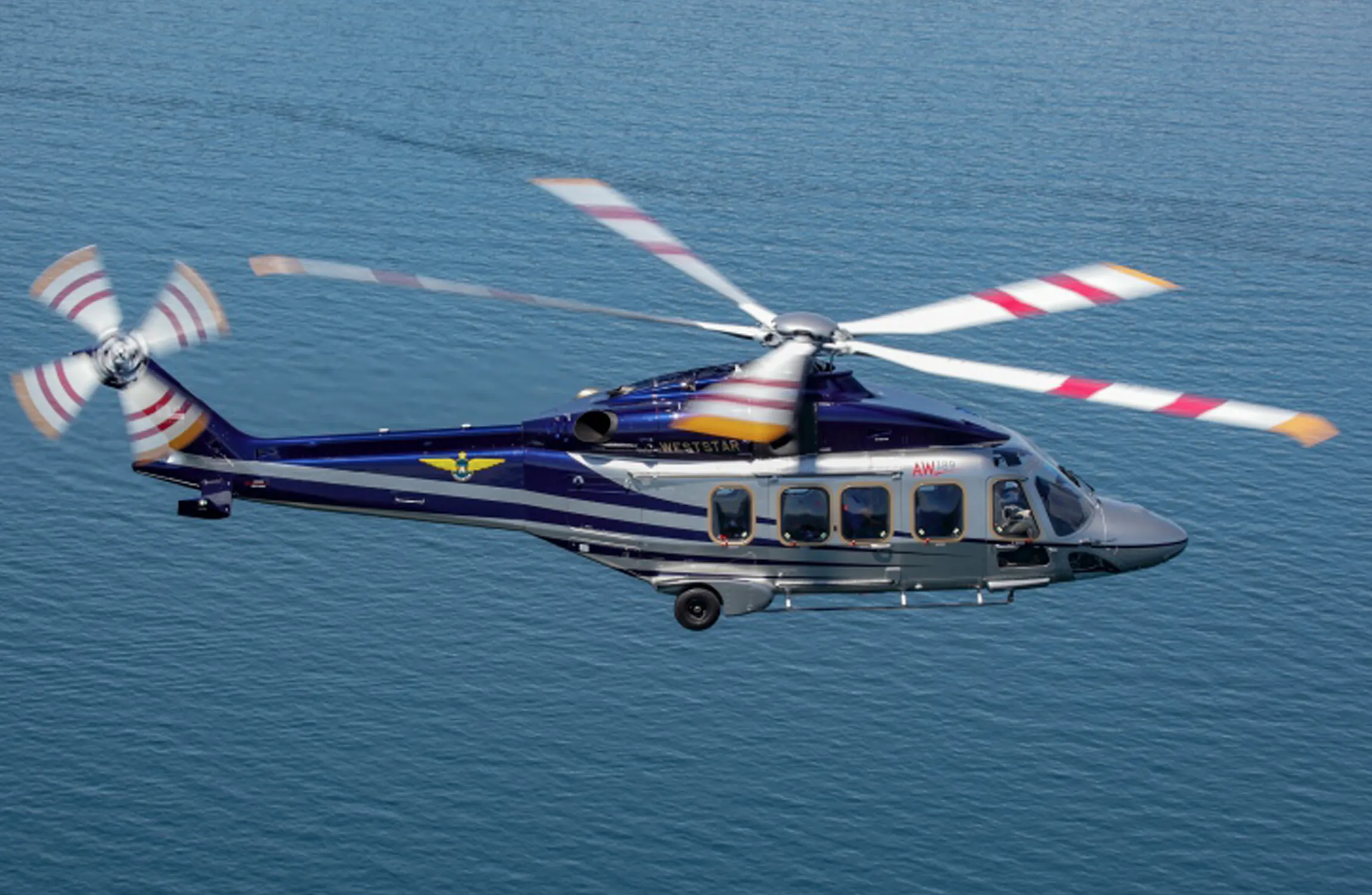 A silver helicopter flying over the sea