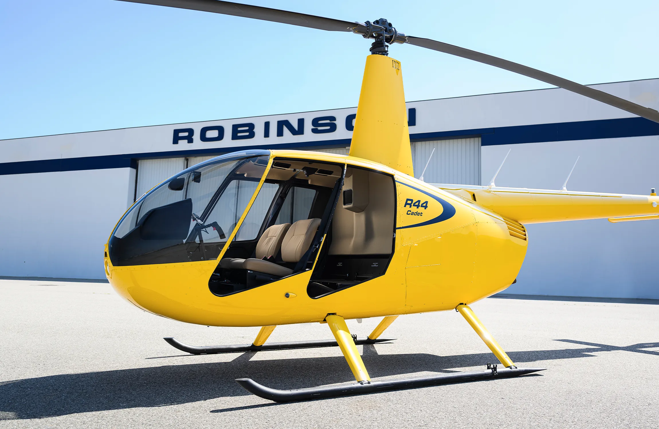A yellow helicopter parked in front of a hangar