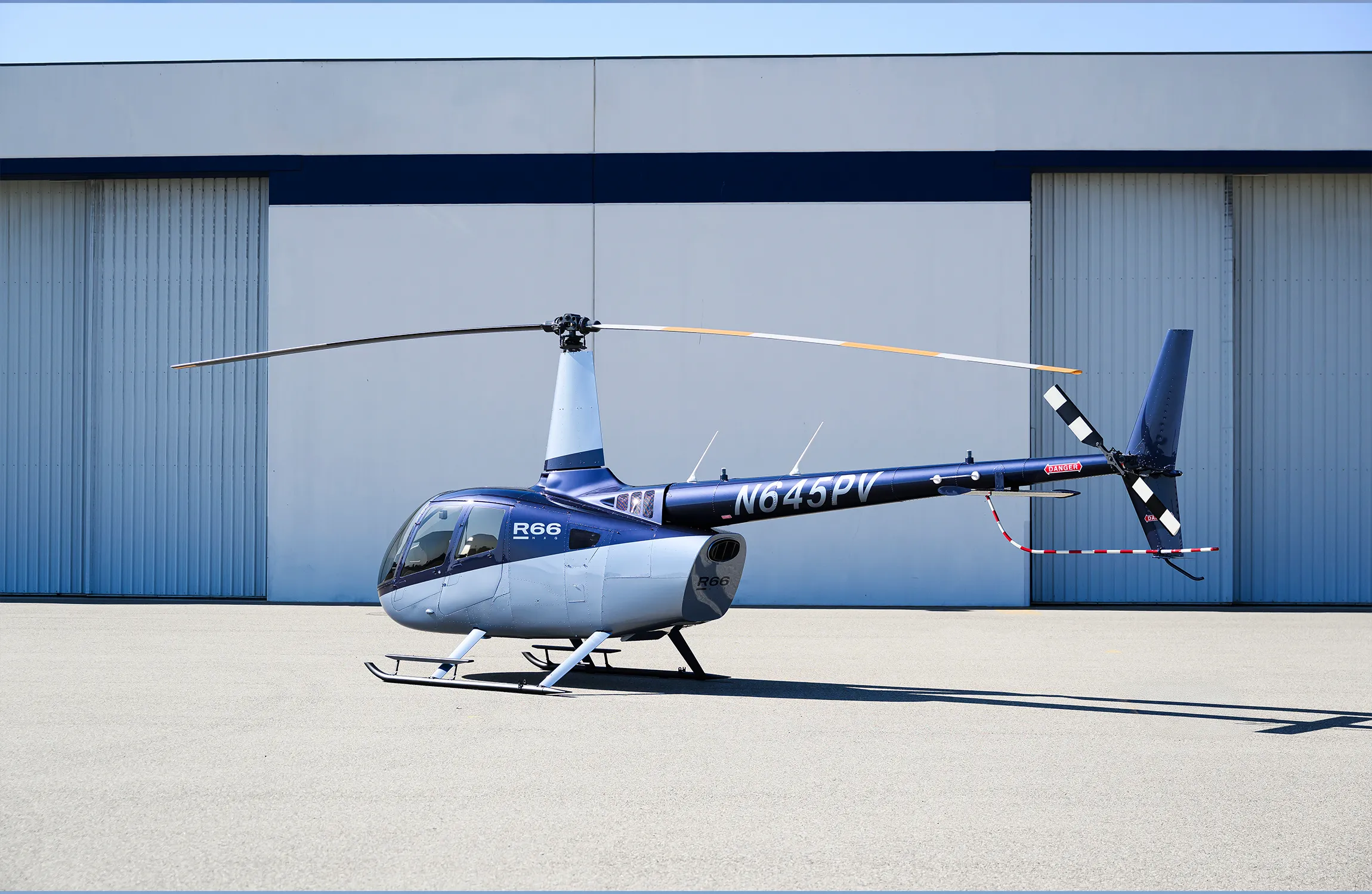 A blue helicopter parked in front of a hangar