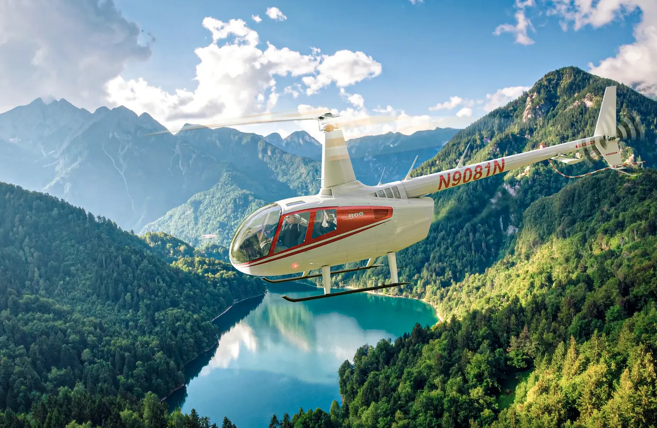 A white helicopter flying over a lake