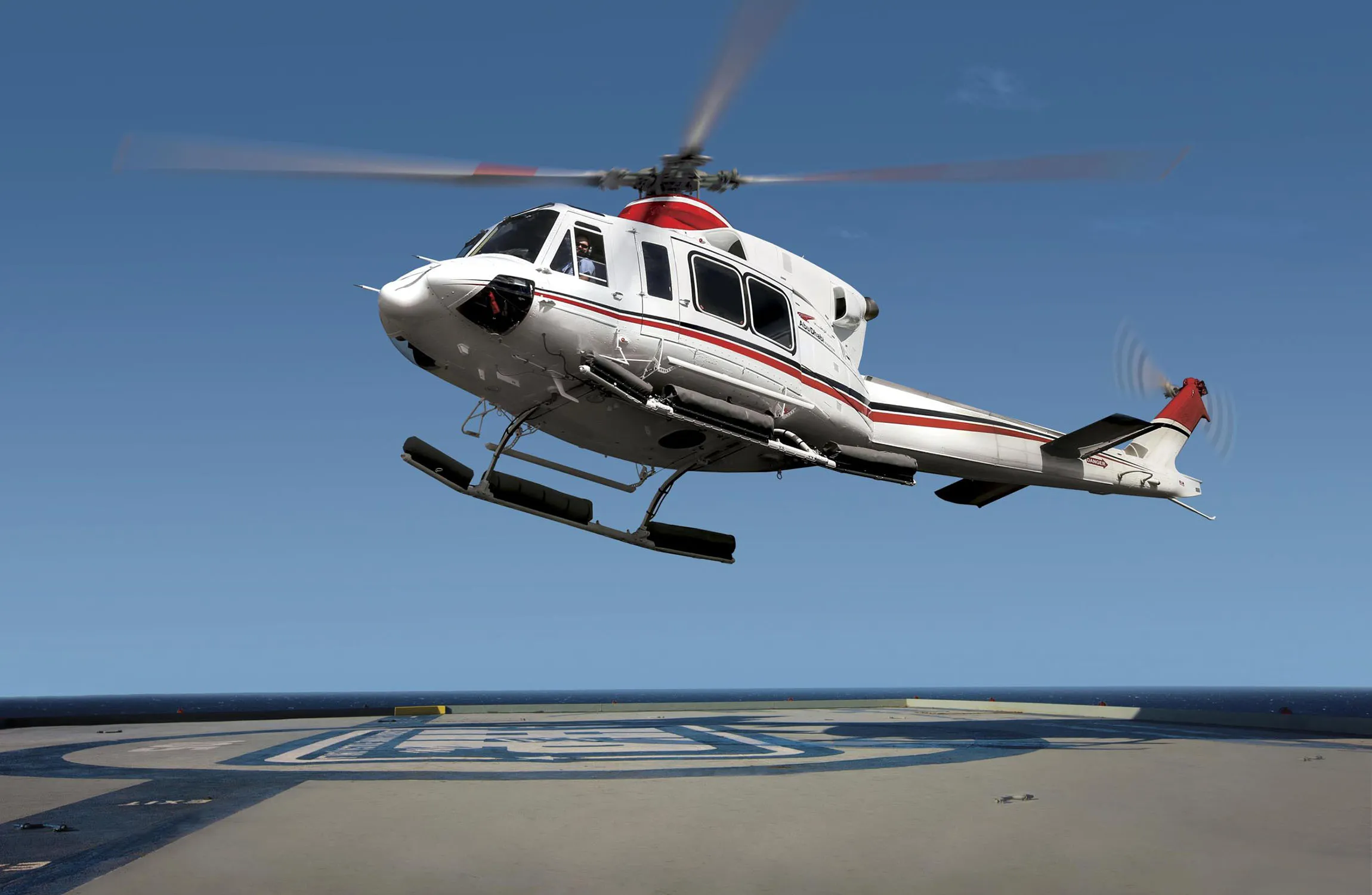 A white helicopter coming in to land on a heliport