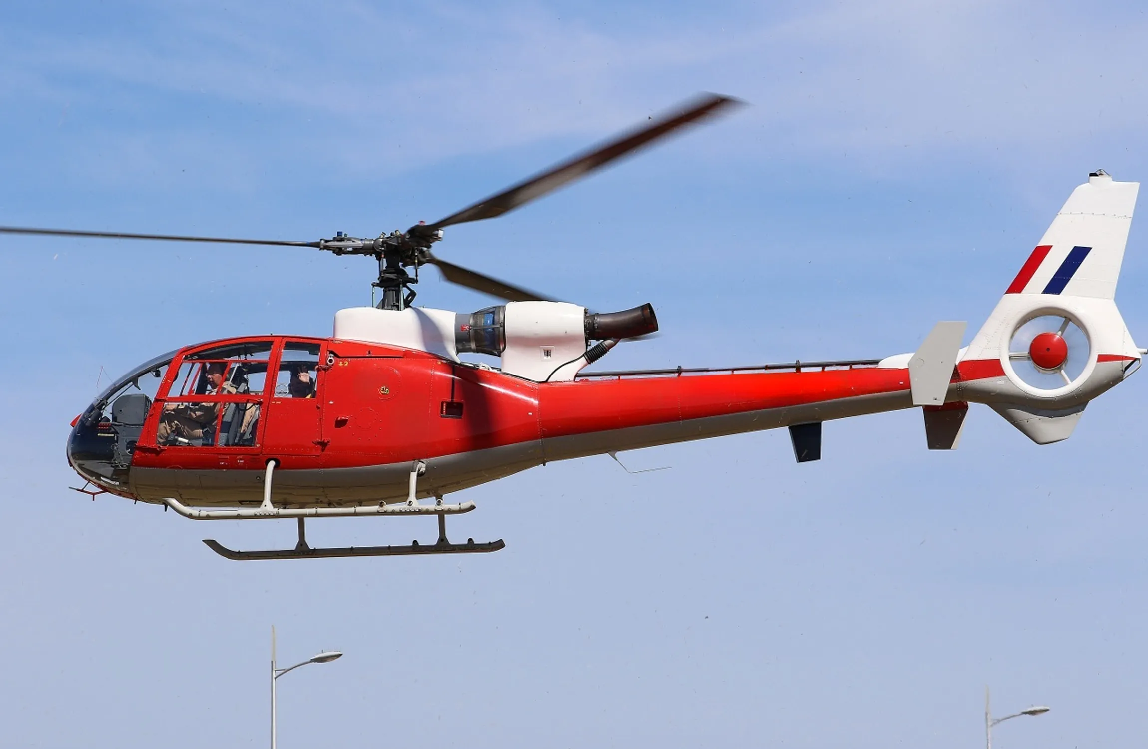 A red helicopter in a blue sky