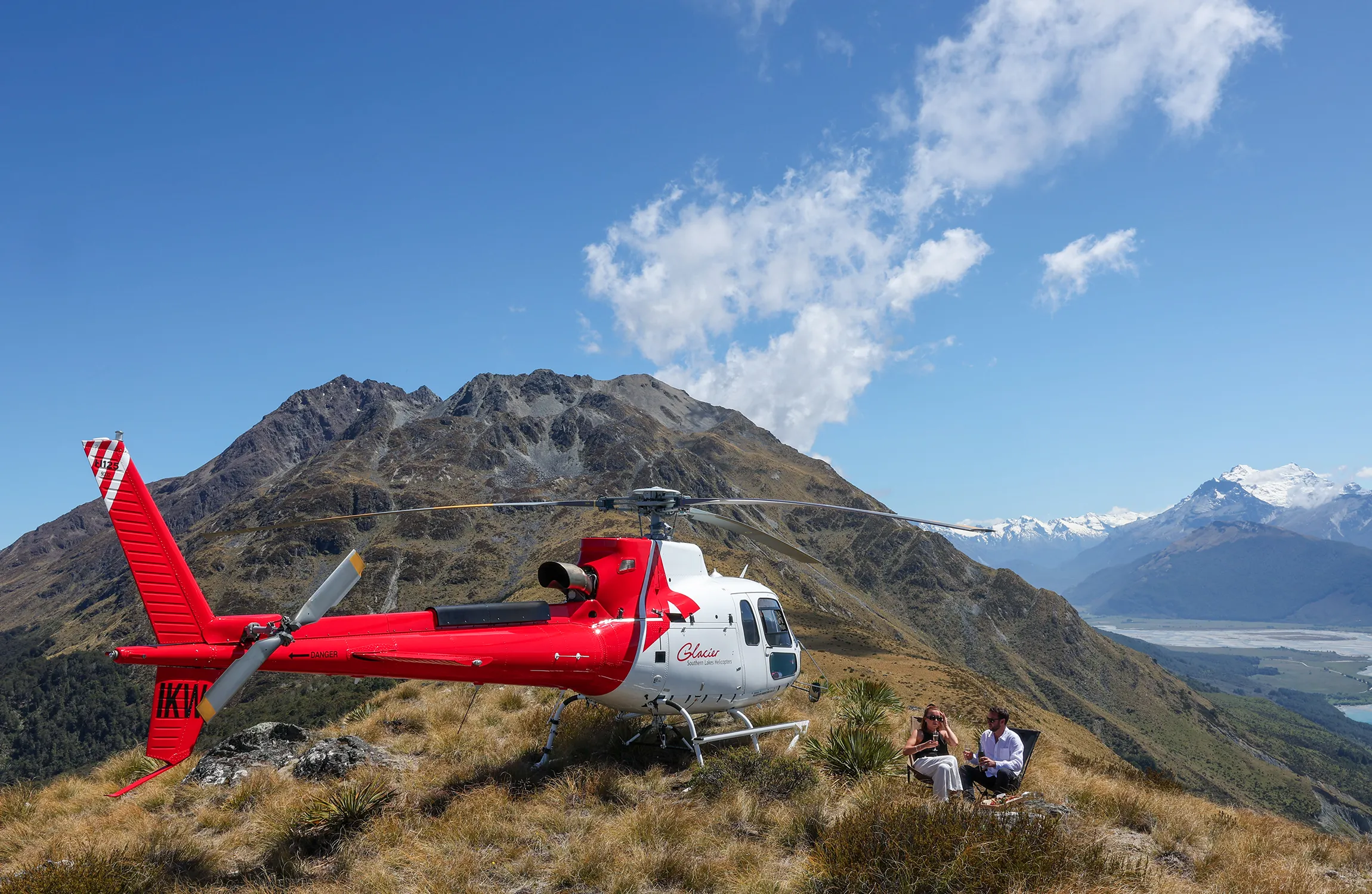 A white and red helicopter perched on top of a mountain