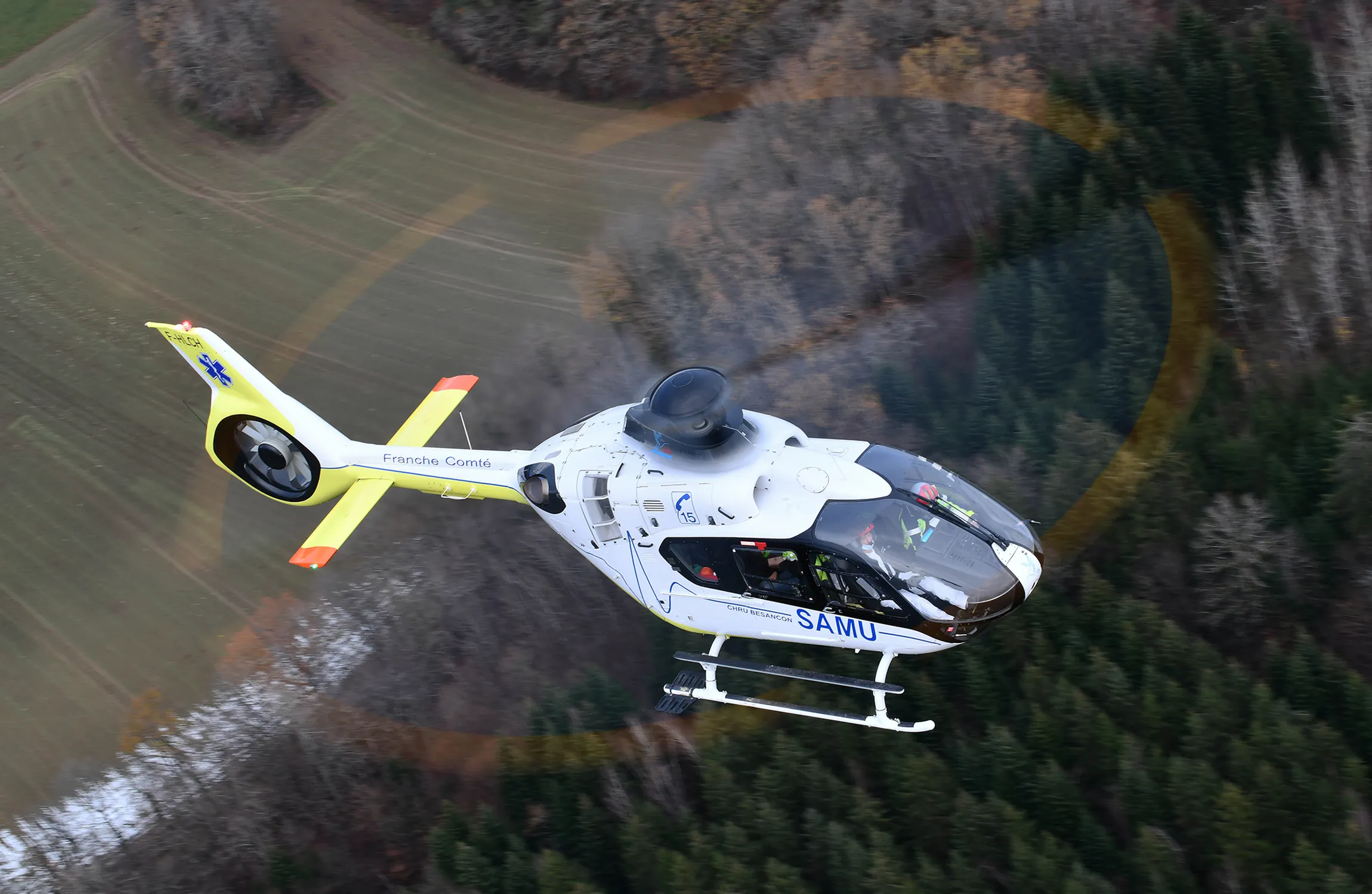 A medical helicopter flying over a forest