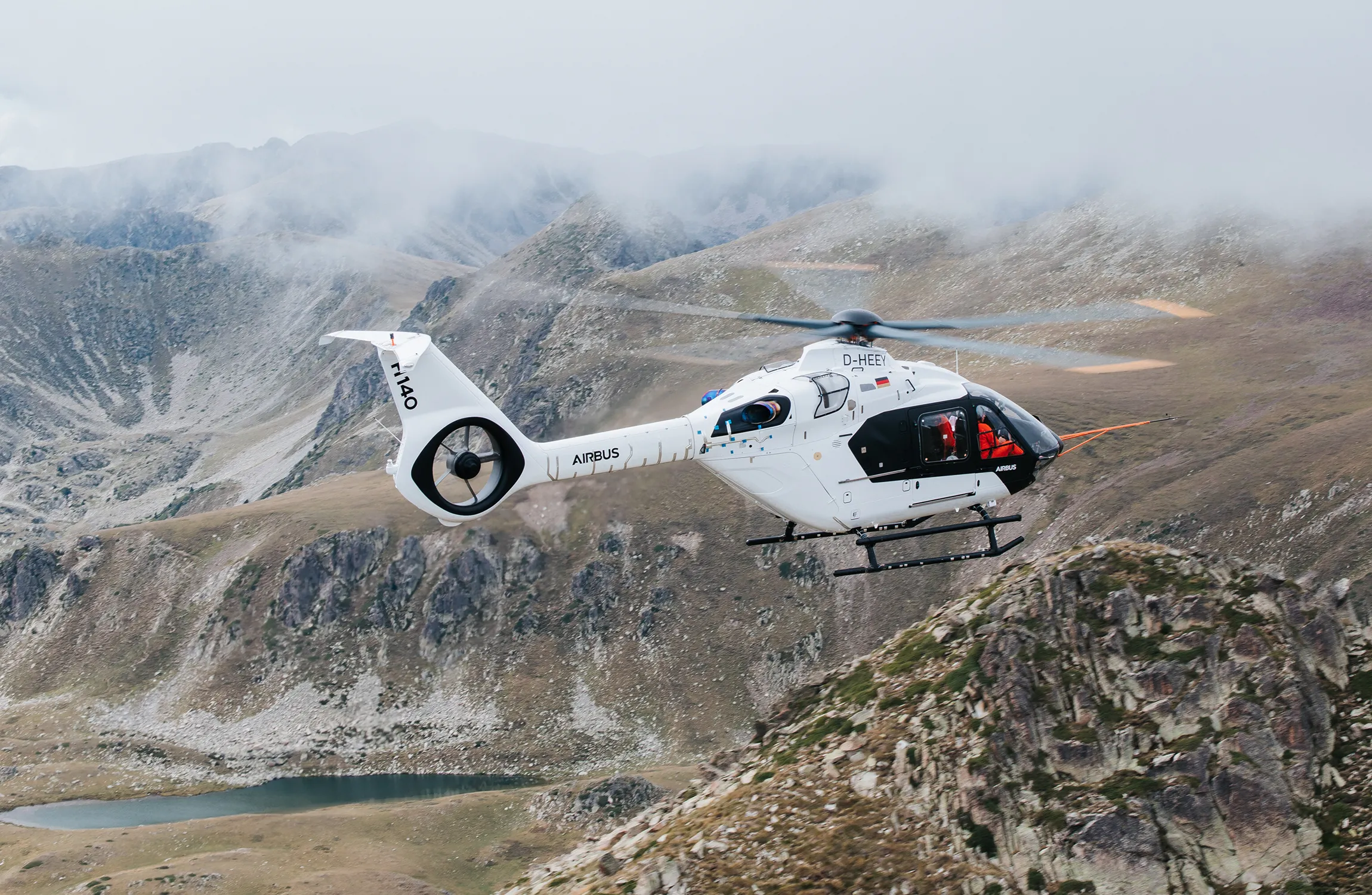 A white helicopter flying among mountains
