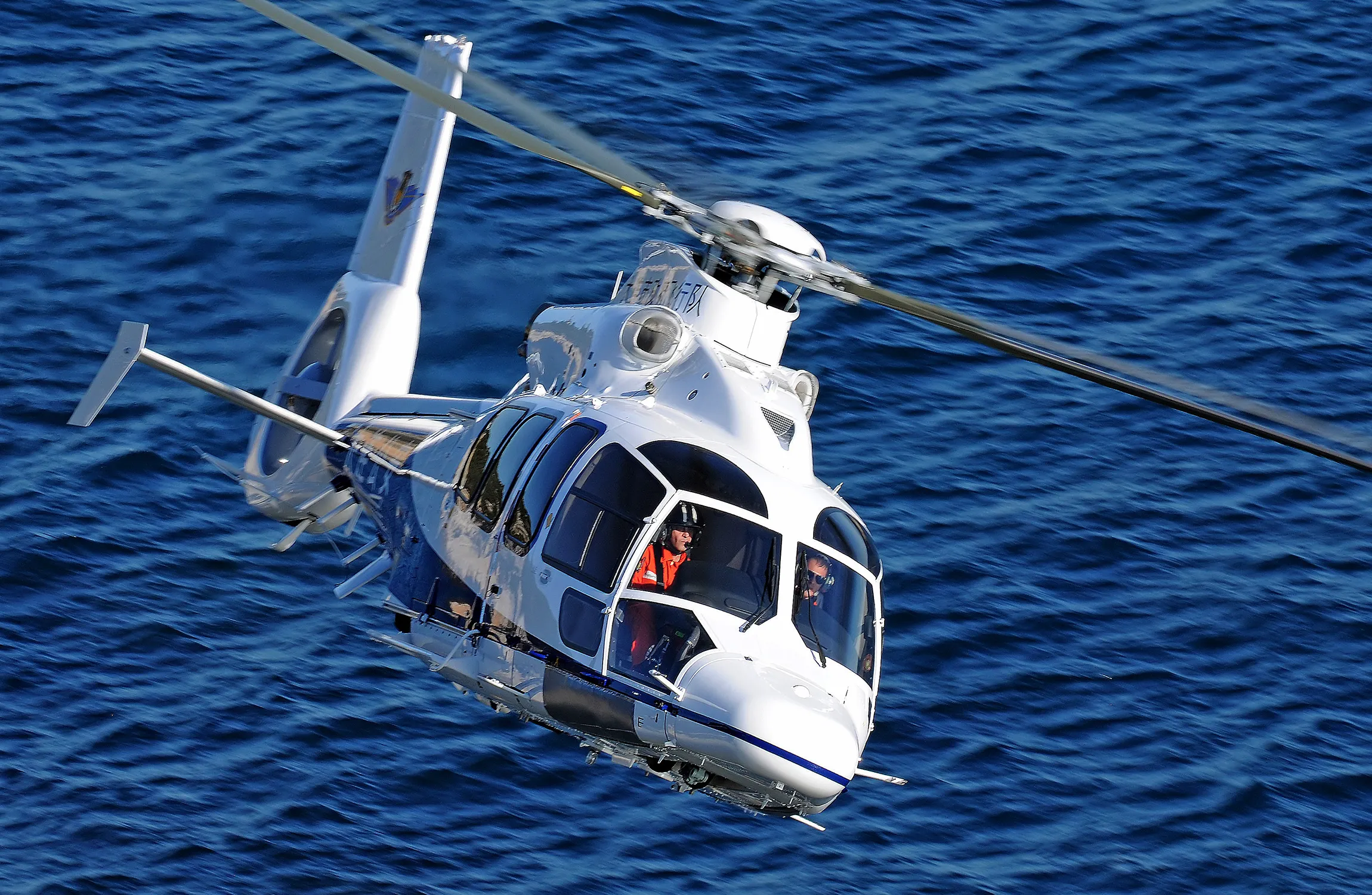 An white helicopter flying over water