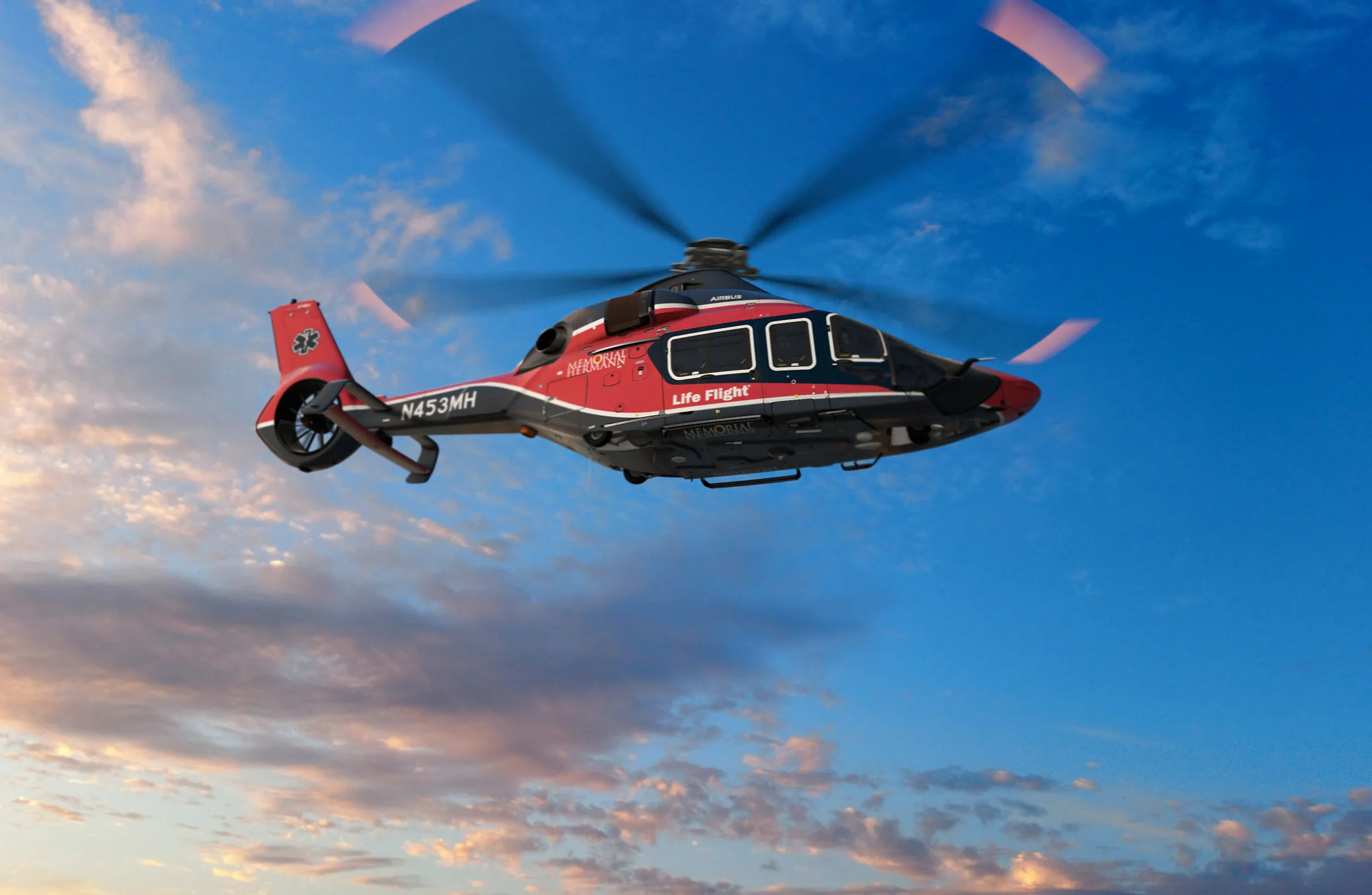 A red and black helicopter flying in the sky
