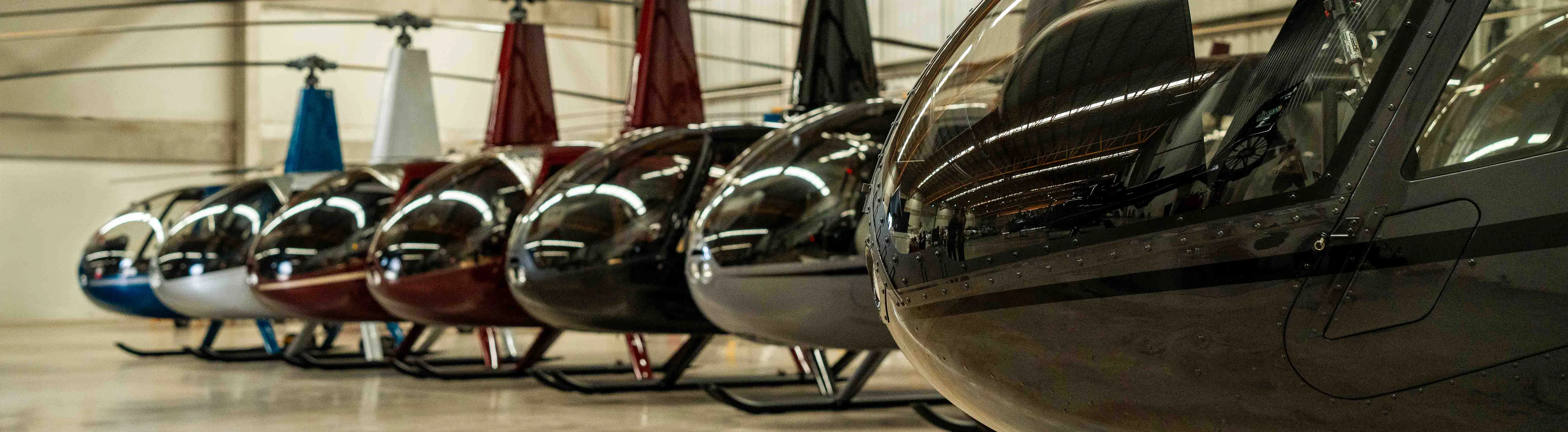 A row of helicopters parked in a hangar