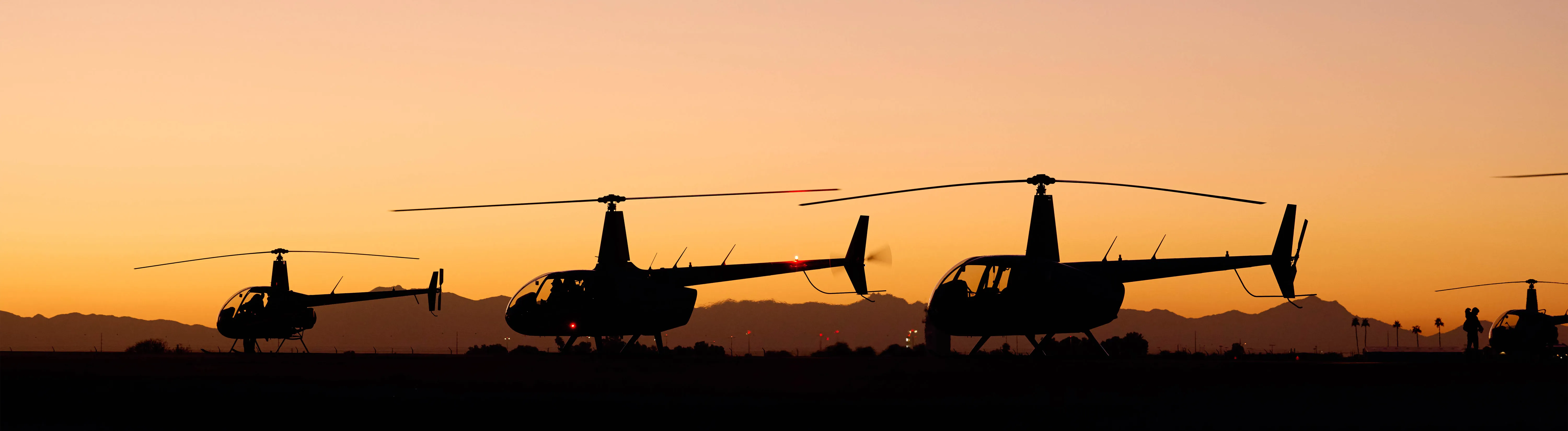 A string of parked helicopters at dusk